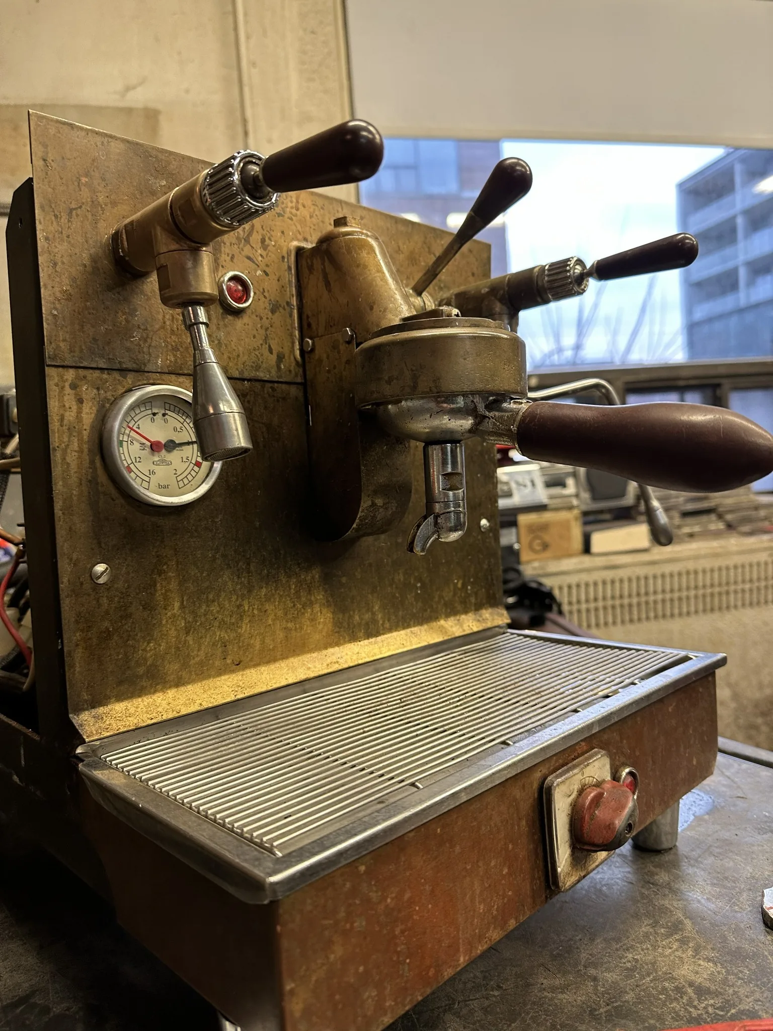 Vintage brass espresso machine on a repair bench